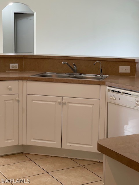 kitchen featuring dishwasher, white cabinets, sink, and light tile floors