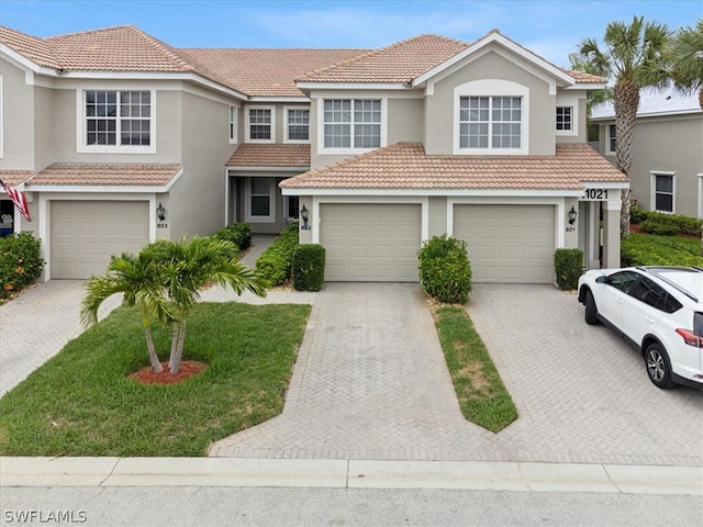 view of front facade featuring a tile roof, decorative driveway, and stucco siding