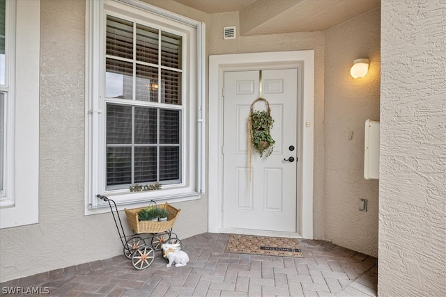 property entrance featuring visible vents and stucco siding