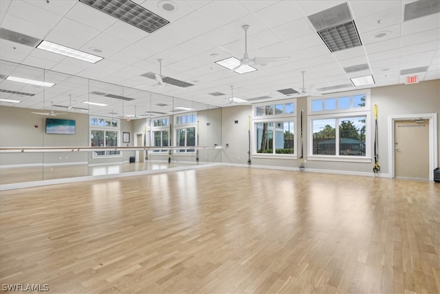 workout room featuring a paneled ceiling, ceiling fan, and light wood-type flooring