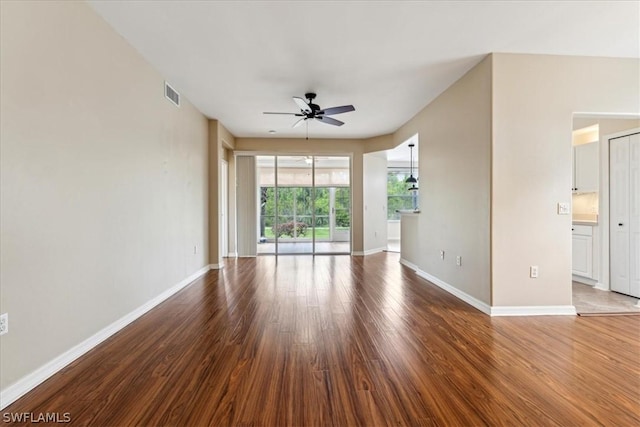 spare room featuring visible vents, ceiling fan, baseboards, and wood finished floors