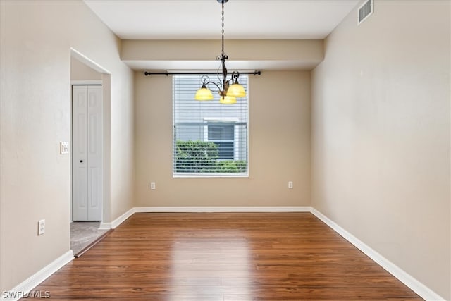 spare room with wood-type flooring and a chandelier