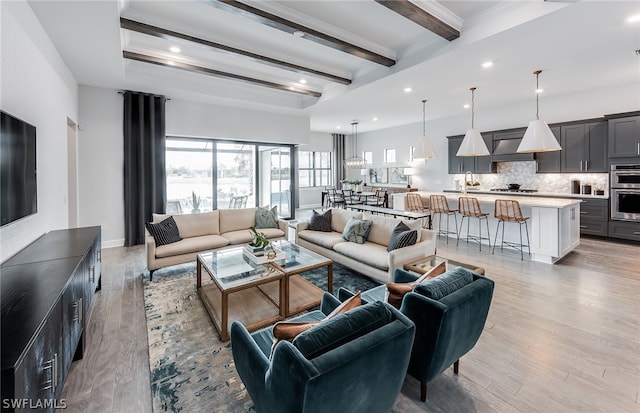 living room featuring light hardwood / wood-style flooring, beam ceiling, and sink