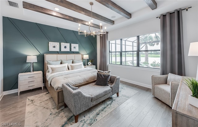 bedroom with hardwood / wood-style floors, beamed ceiling, and a chandelier