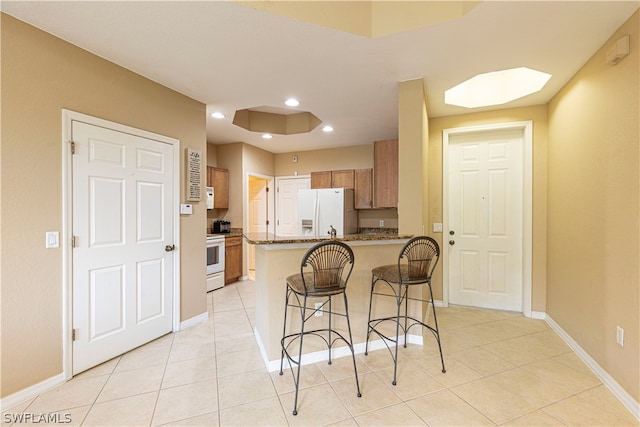 kitchen featuring white fridge with ice dispenser, light tile flooring, and stove