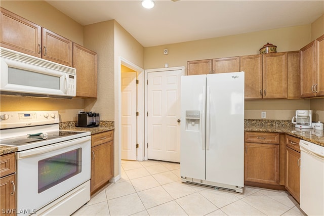 kitchen with white appliances, light tile floors, and dark stone counters