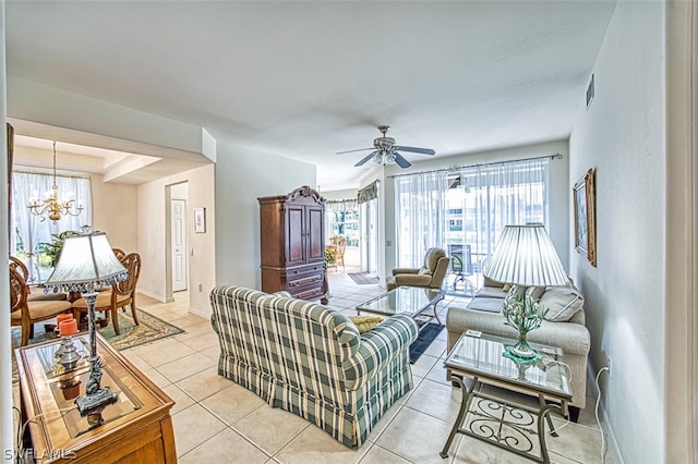 living room with a raised ceiling, light tile floors, and ceiling fan with notable chandelier