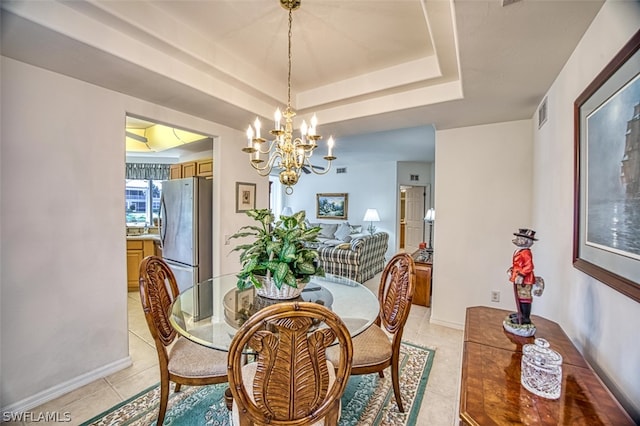 tiled dining space featuring an inviting chandelier and a tray ceiling