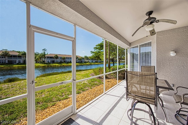 sunroom / solarium with a healthy amount of sunlight, a water view, and ceiling fan