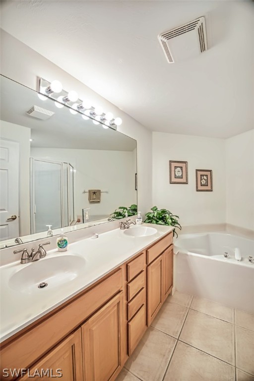 bathroom featuring tile flooring, oversized vanity, double sink, and independent shower and bath