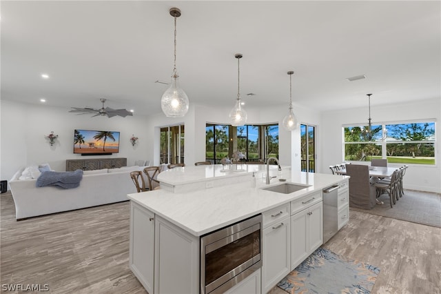 kitchen featuring sink, stainless steel appliances, light wood-type flooring, and a center island with sink