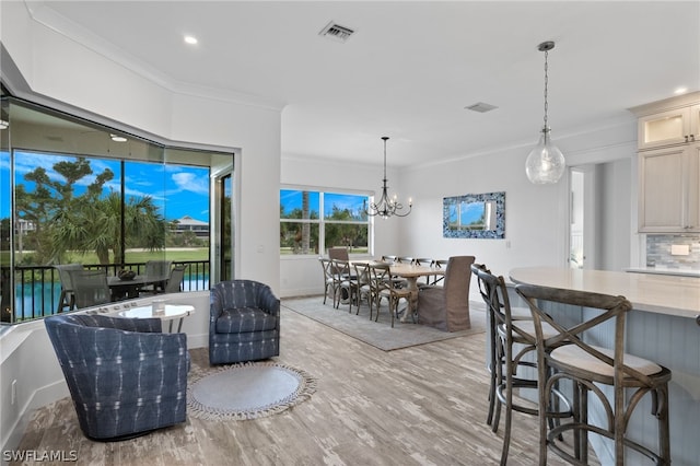 interior space featuring a water view, light hardwood / wood-style floors, a chandelier, and ornamental molding