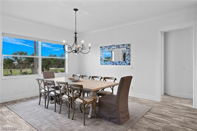 dining room with a chandelier, light wood-type flooring, and crown molding