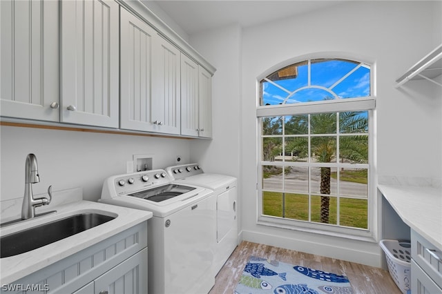 laundry room with plenty of natural light, cabinets, light wood-type flooring, and washer and dryer