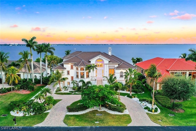 mediterranean / spanish house with a yard and a water view