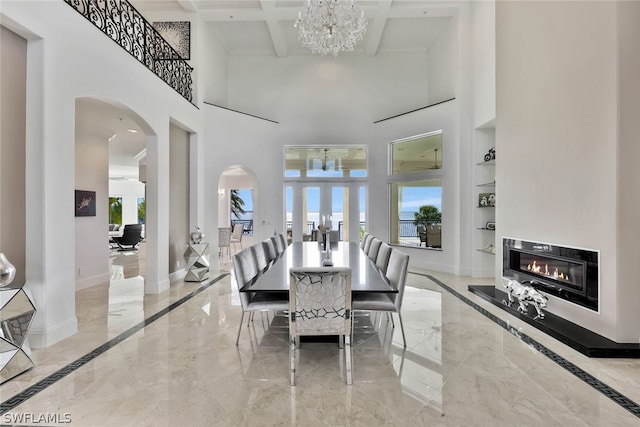 dining room featuring beamed ceiling, light tile floors, coffered ceiling, a high ceiling, and a chandelier