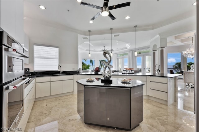 kitchen with a kitchen island, sink, white cabinetry, hanging light fixtures, and kitchen peninsula