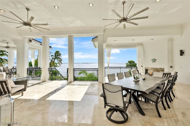 tiled dining space with a water view, ceiling fan, and ornamental molding