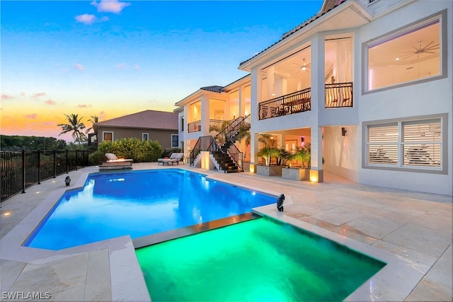 pool at dusk with an in ground hot tub and a patio area