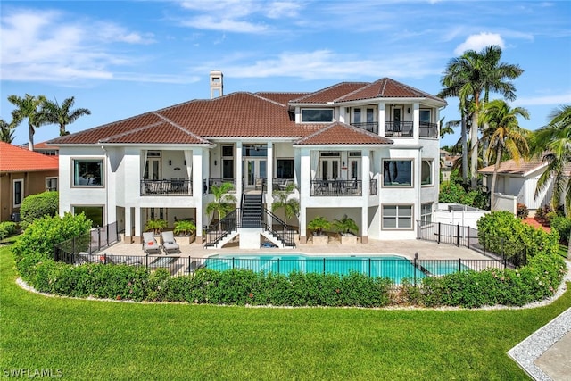 back of house featuring a fenced in pool, a patio area, a yard, and a balcony