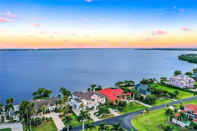 aerial view at dusk featuring a water view