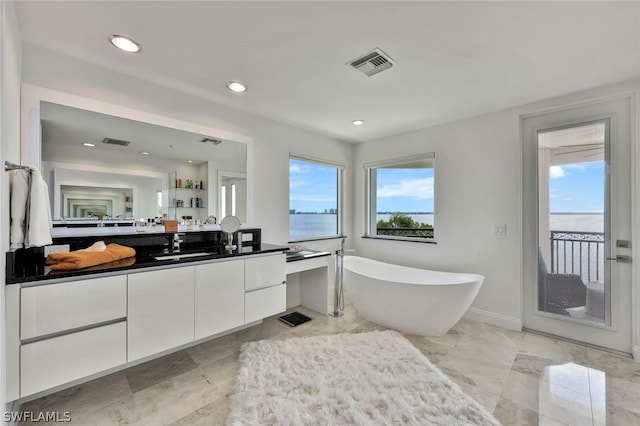 bathroom with tile floors, vanity with extensive cabinet space, and a bathtub