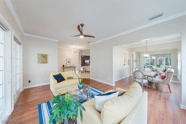 living room with ceiling fan with notable chandelier, wood-type flooring, and crown molding