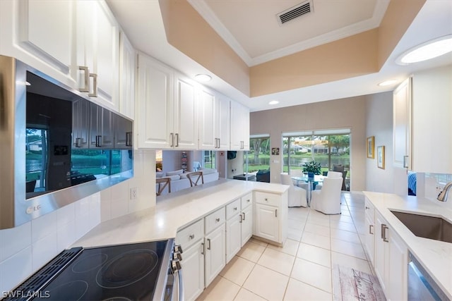 kitchen with sink, tasteful backsplash, kitchen peninsula, crown molding, and white cabinets