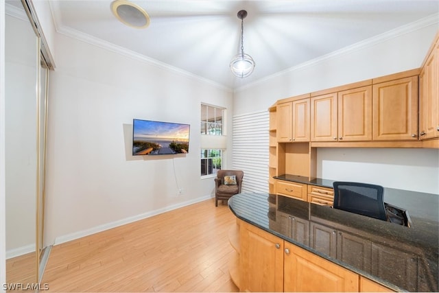 kitchen featuring pendant lighting, dark stone countertops, ornamental molding, and light hardwood / wood-style flooring