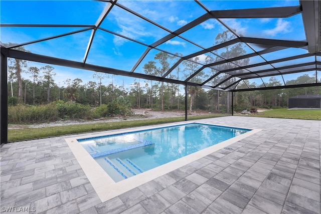 view of swimming pool featuring a patio area, a yard, and glass enclosure