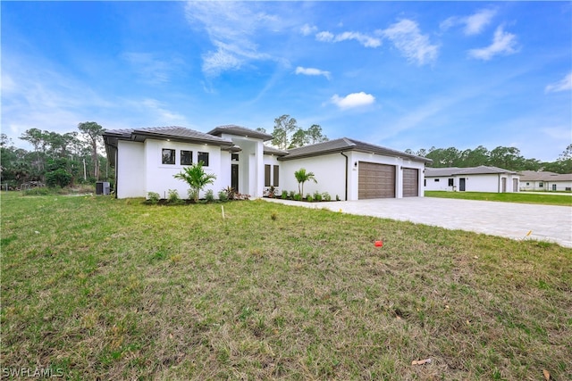 view of front facade featuring a front yard, a garage, and central AC unit