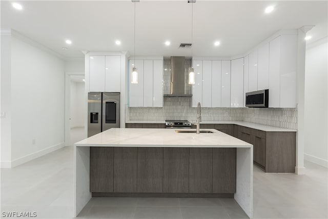 kitchen with white cabinets, ornamental molding, wall chimney range hood, stainless steel appliances, and sink