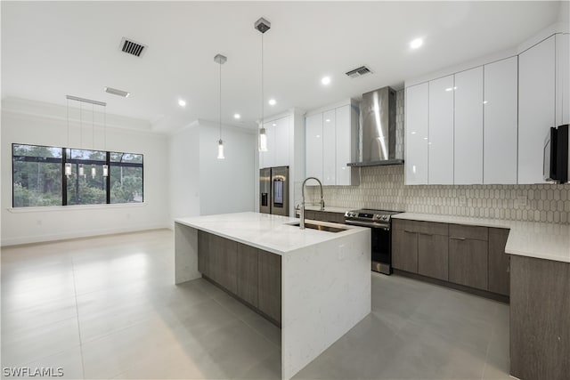 kitchen with appliances with stainless steel finishes, tasteful backsplash, wall chimney exhaust hood, sink, and pendant lighting