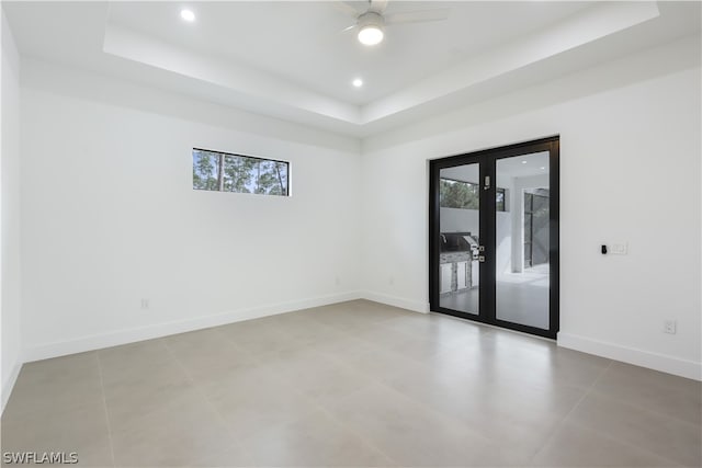 tiled spare room with plenty of natural light, french doors, and a tray ceiling