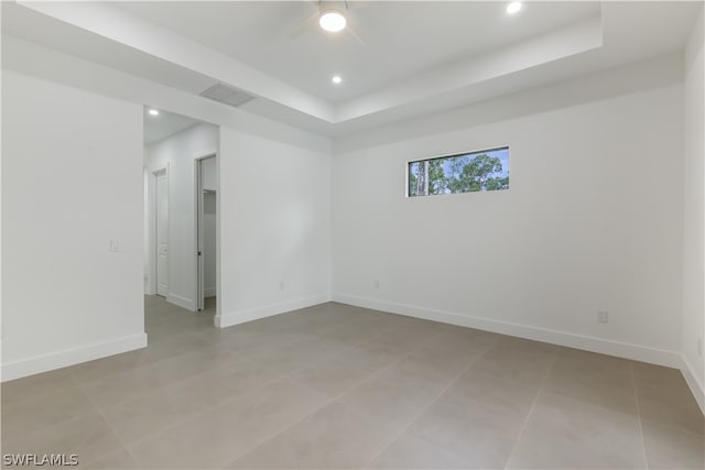 tiled spare room with a tray ceiling