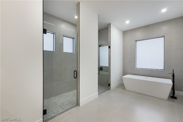 bathroom featuring tile walls, tile flooring, and independent shower and bath