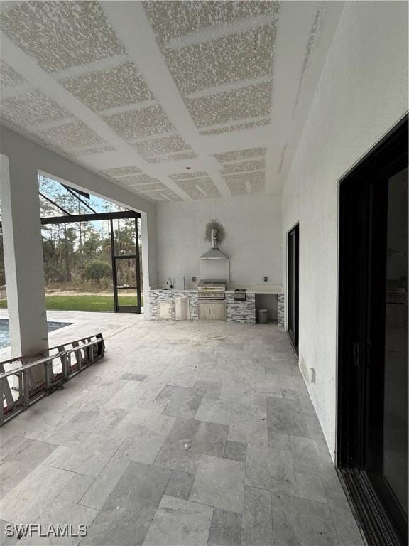 view of patio with area for grilling, glass enclosure, and exterior kitchen