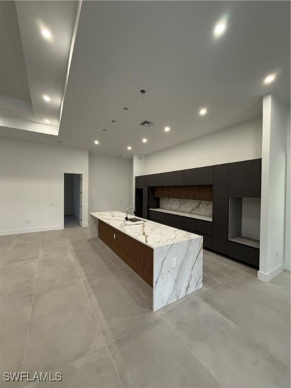 kitchen featuring light stone countertops and a large island with sink