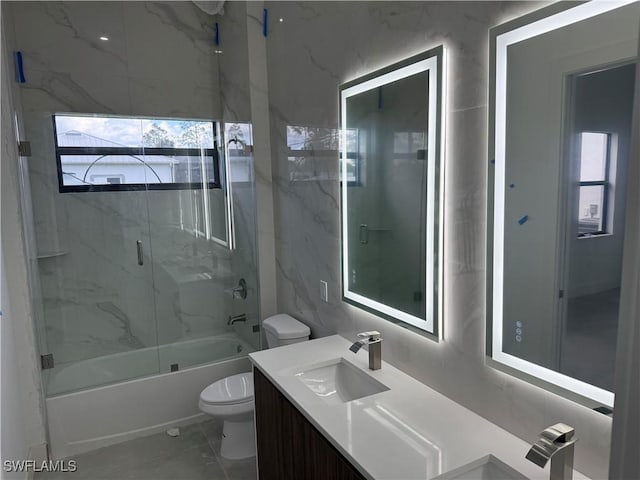 full bathroom featuring vanity, shower / bath combination with glass door, and toilet