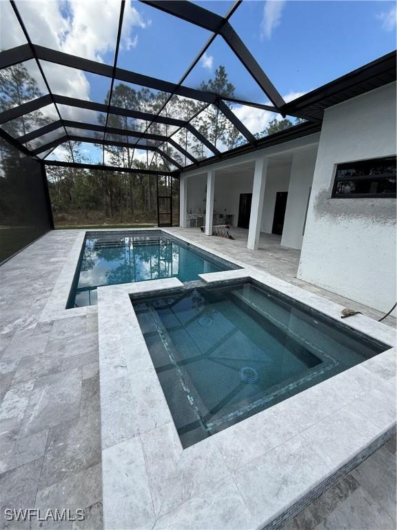 view of pool featuring an in ground hot tub, a lanai, and a patio