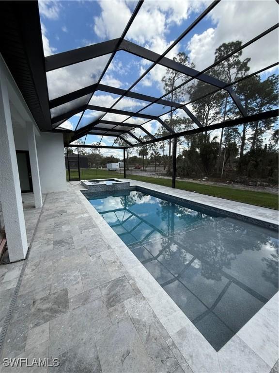 view of swimming pool featuring a patio area, an in ground hot tub, and glass enclosure