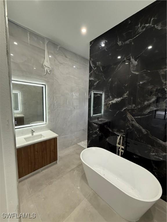 bathroom with vanity, tile walls, and a bathtub