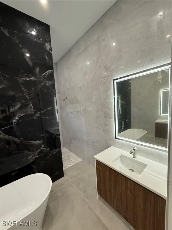 bathroom featuring vanity, tiled shower, and tile walls