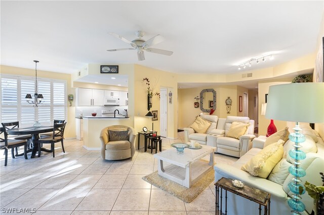 tiled living room featuring ceiling fan, track lighting, and sink