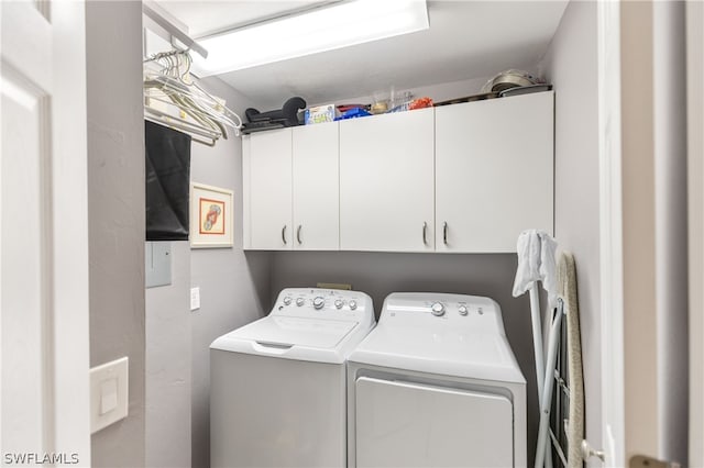 laundry room featuring washer and clothes dryer and cabinets