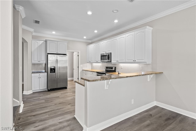 kitchen featuring appliances with stainless steel finishes, wood-type flooring, kitchen peninsula, and white cabinets