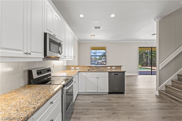 kitchen featuring white cabinets, light hardwood / wood-style flooring, kitchen peninsula, appliances with stainless steel finishes, and sink