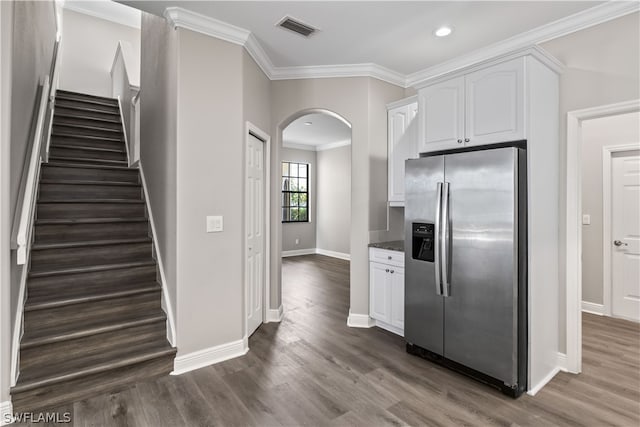 kitchen featuring stainless steel fridge, crown molding, dark wood-type flooring, dark stone countertops, and white cabinets