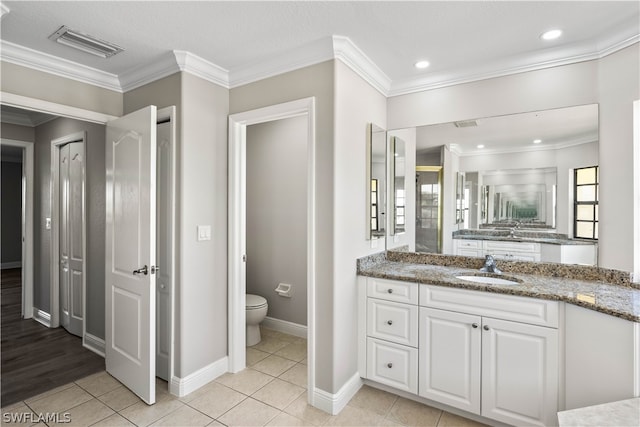 bathroom featuring hardwood / wood-style flooring, crown molding, toilet, and vanity