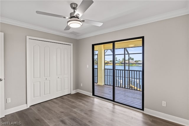 unfurnished bedroom featuring a water view, ceiling fan, hardwood / wood-style flooring, a closet, and ornamental molding